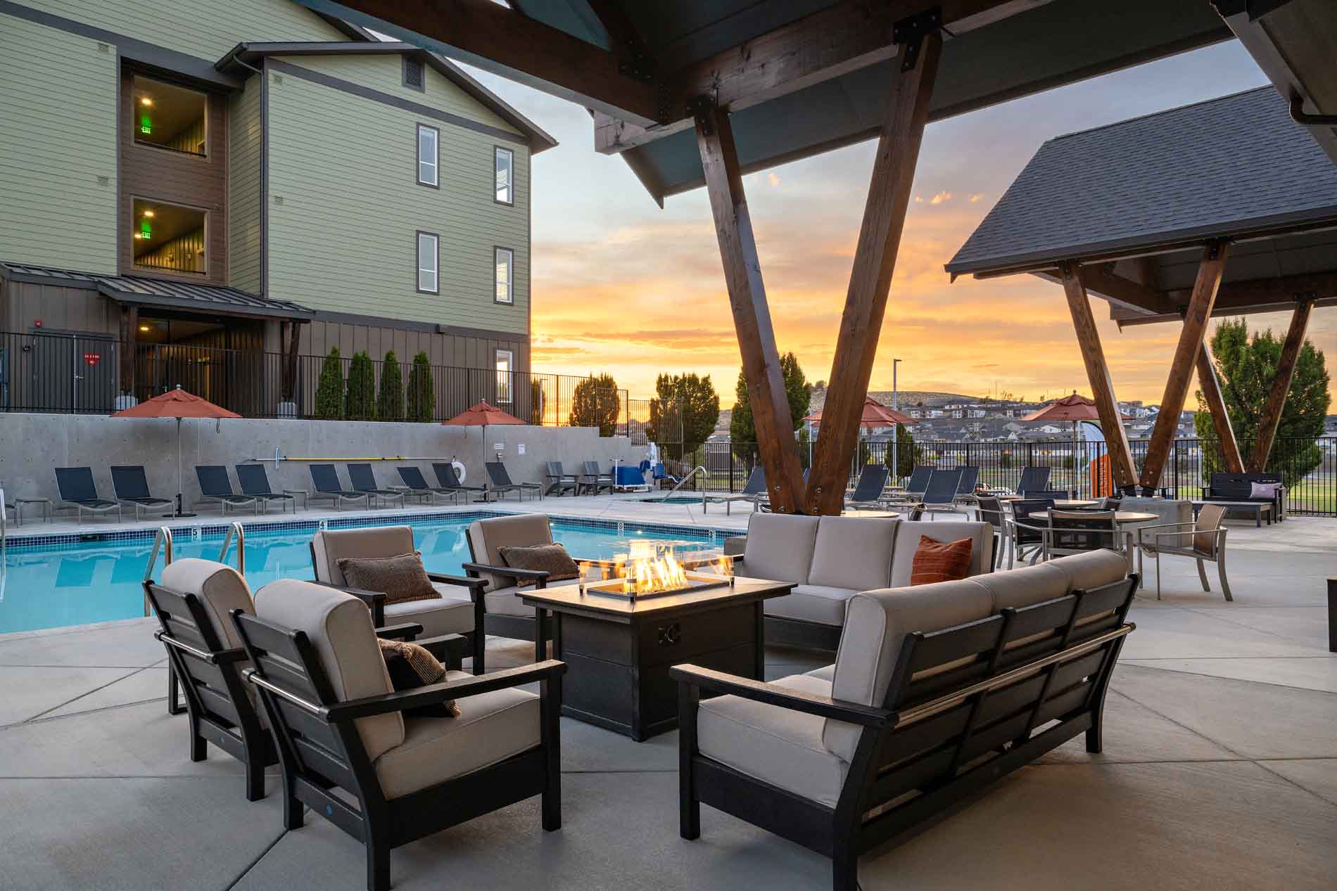 Outdoor lounge with fire pit and pool at a Cordillera community at sunset