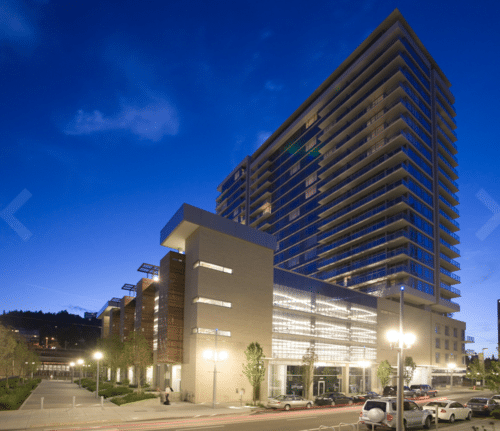 Glass residential tower above a mixed-use podium at night