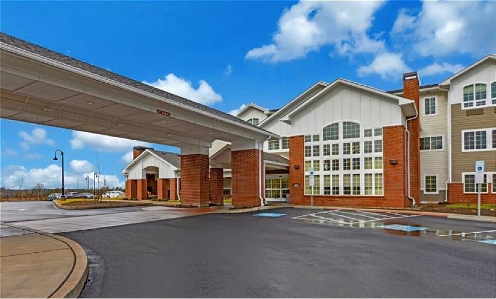 Brick and white-sided senior living community with a covered drop-off