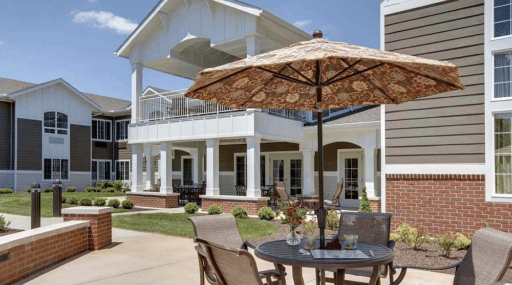 Senior living patio with umbrella seating and a two-story veranda