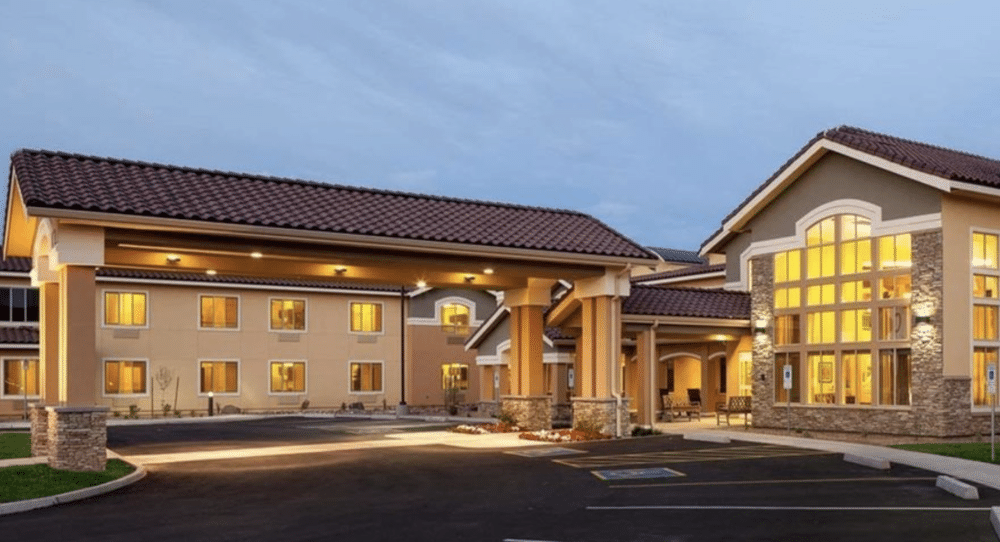 Senior living community with a tile-roofed porte-cochère glowing at dusk