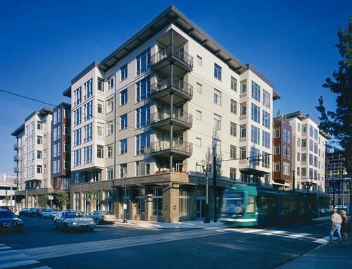 Corner mid-rise apartment building with a streetcar passing below
