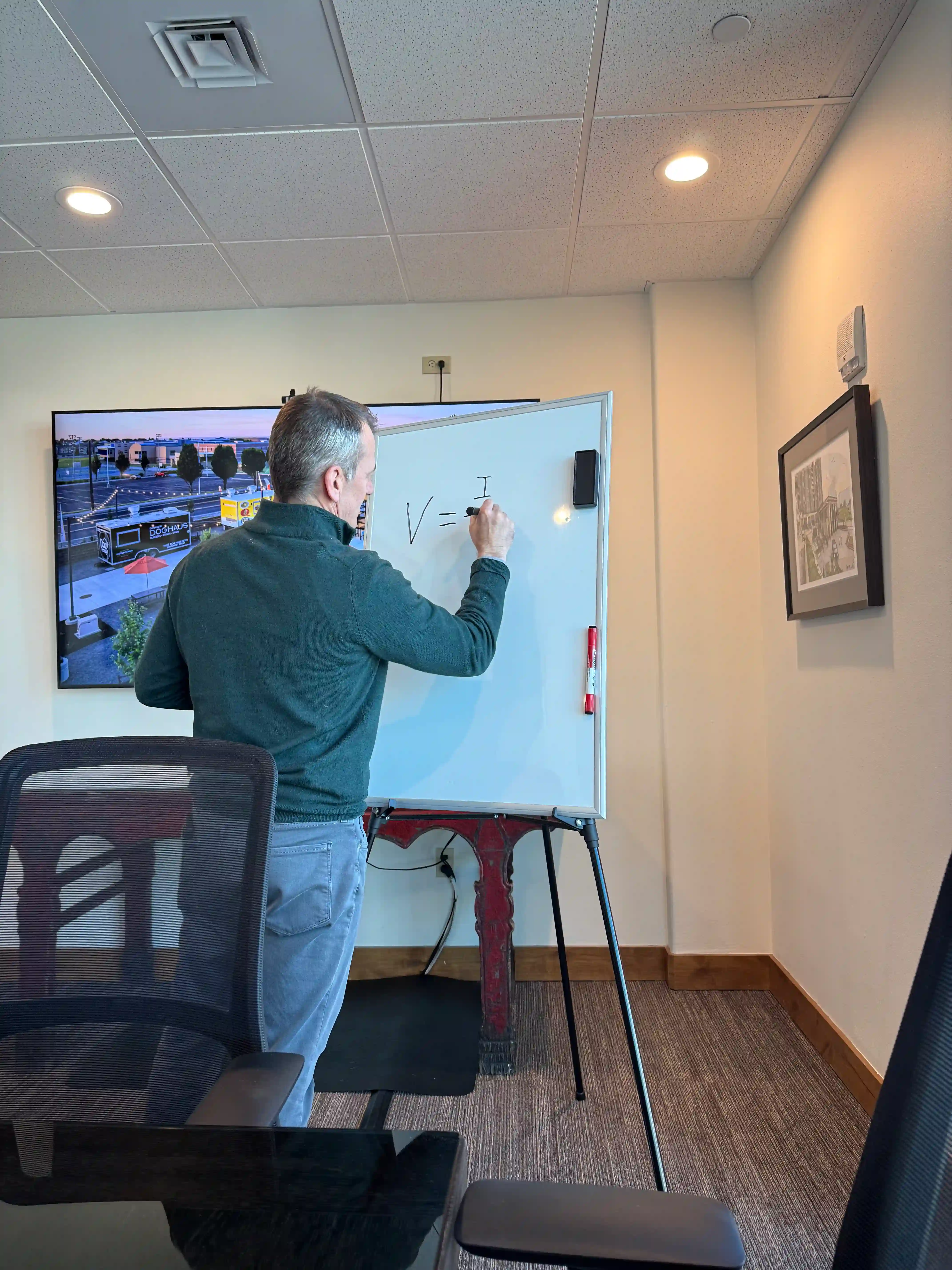 Tom writing on a whiteboard during a meeting in the Cordillera conference room