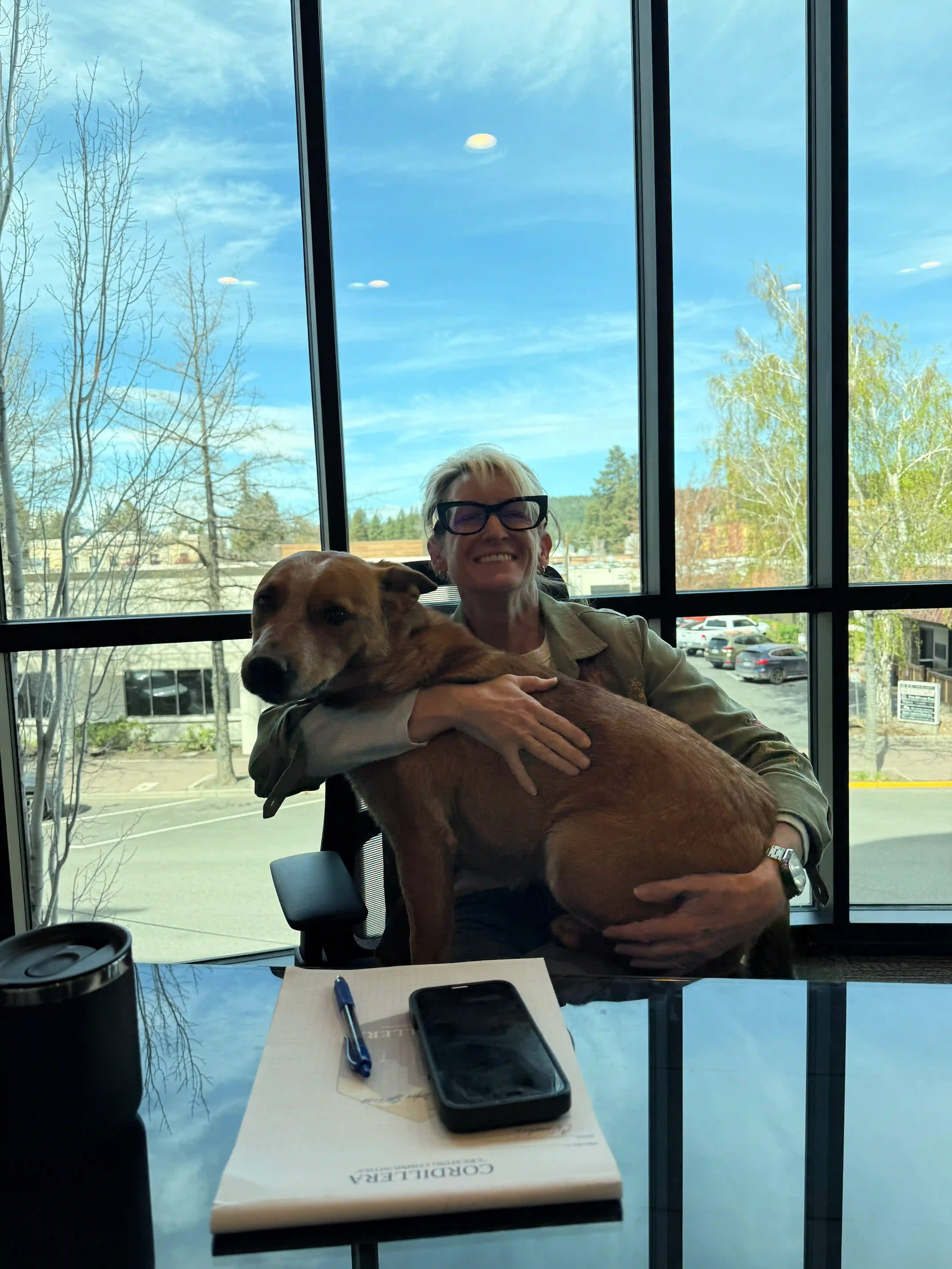 Shannon holding Dale at her desk with a view of downtown Bend